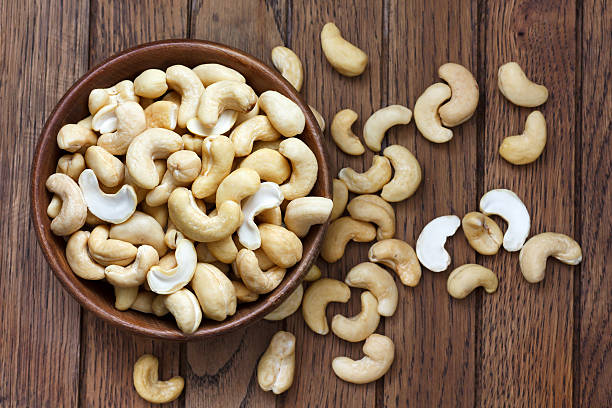 wooden bowl of cashew nuts from above. on dark wood.